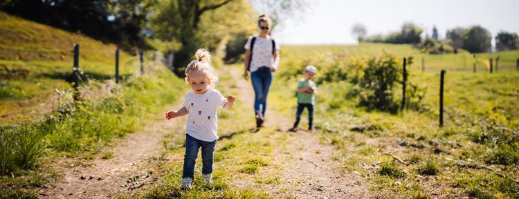 Kleines Mädchen geht mit ihrer Familie im Frühjahr auf den Feldern spazieren
